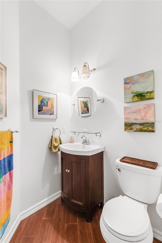 bathroom with baseboards, toilet, wood finished floors, and vanity