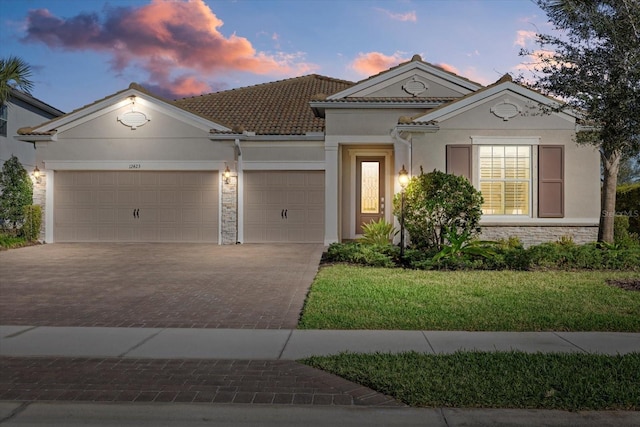 view of front facade with an attached garage, stone siding, decorative driveway, and stucco siding