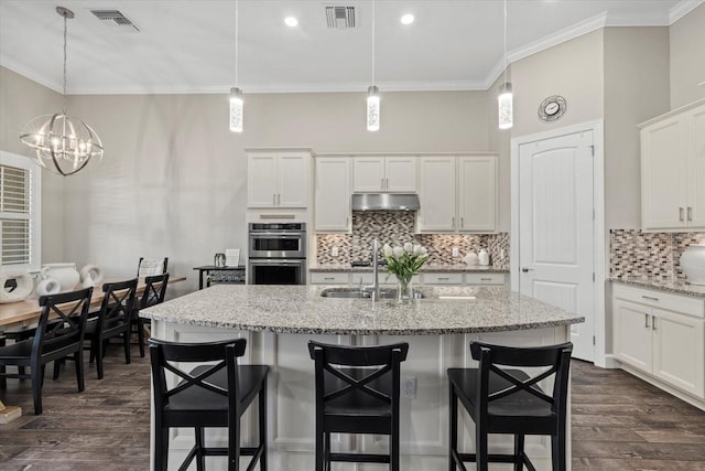 kitchen featuring dark wood finished floors, visible vents, crown molding, and under cabinet range hood