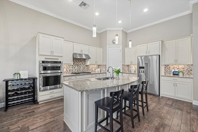 kitchen with under cabinet range hood, stainless steel appliances, a sink, visible vents, and white cabinets