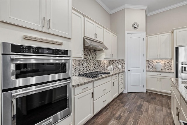 kitchen featuring under cabinet range hood, stainless steel appliances, white cabinets, dark wood-style floors, and crown molding