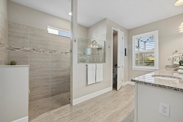 bathroom with baseboards, plenty of natural light, toilet, and a walk in shower