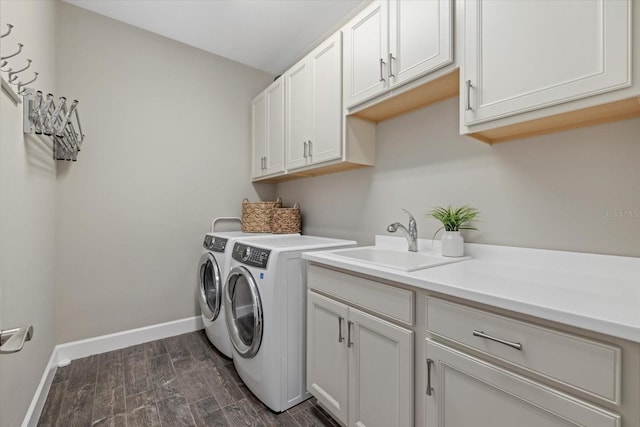 washroom featuring dark wood-style floors, cabinet space, a sink, independent washer and dryer, and baseboards