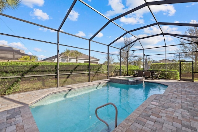 view of pool featuring glass enclosure, a pool with connected hot tub, and a patio