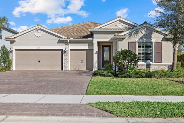 view of front of property with decorative driveway, a tile roof, stucco siding, an attached garage, and stone siding