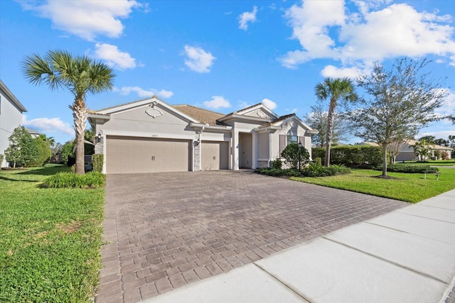 view of front of property featuring a front yard, decorative driveway, an attached garage, and stucco siding