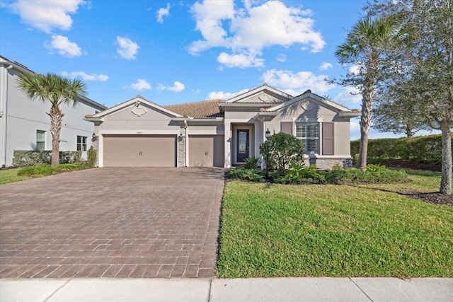 view of front of house featuring a garage, stone siding, a front lawn, and decorative driveway