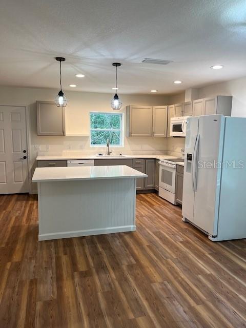 kitchen featuring light countertops, white appliances, hanging light fixtures, and gray cabinetry