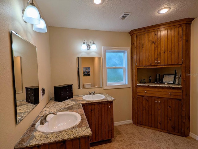 32 Fallen Oak Ln, Palm Coast, FL 32137 - full bathroom featuring double vanity, baseboards, a textured ceiling, and tile patterned flooring