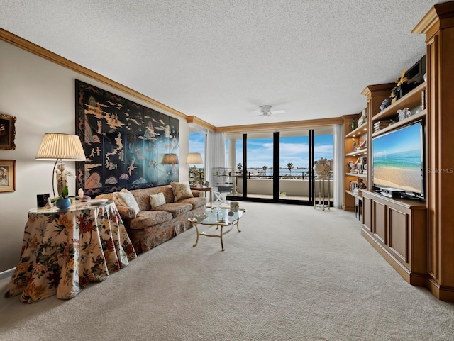 living area with a textured ceiling, carpet floors, ornamental molding, and a ceiling fan