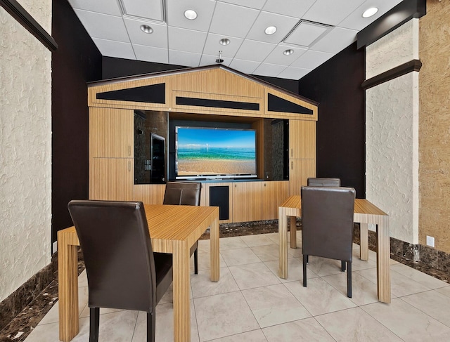 cinema room featuring lofted ceiling, a textured wall, a paneled ceiling, and light tile patterned floors