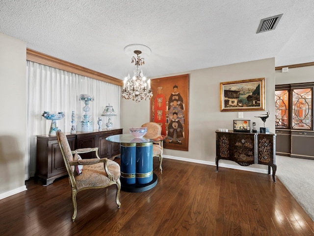 dining area with a textured ceiling, a notable chandelier, visible vents, baseboards, and hardwood / wood-style floors