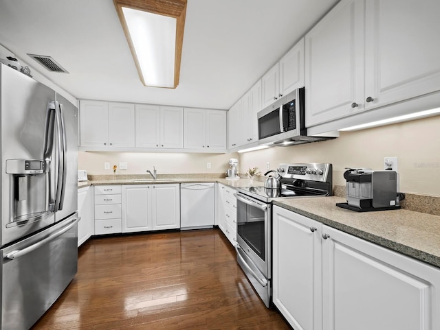 kitchen with stainless steel appliances, visible vents, dark wood finished floors, and white cabinetry