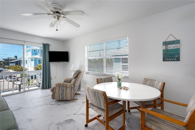 dining room with marble finish floor, ceiling fan, and baseboards