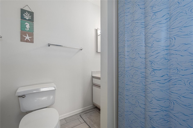 bathroom with baseboards, vanity, and toilet