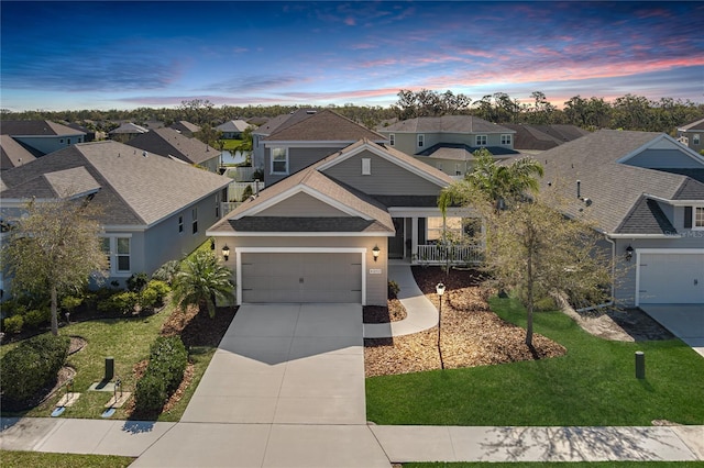 view of front of house featuring concrete driveway, a lawn, a residential view, and a shingled roof