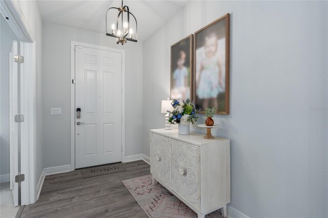 entrance foyer with a notable chandelier, baseboards, and wood finished floors