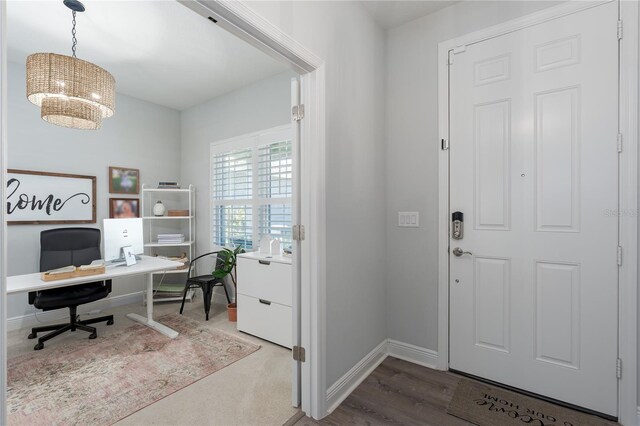 foyer entrance featuring dark wood finished floors, a chandelier, and baseboards