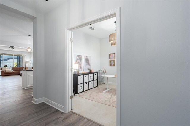 hall featuring visible vents, baseboards, and dark wood finished floors