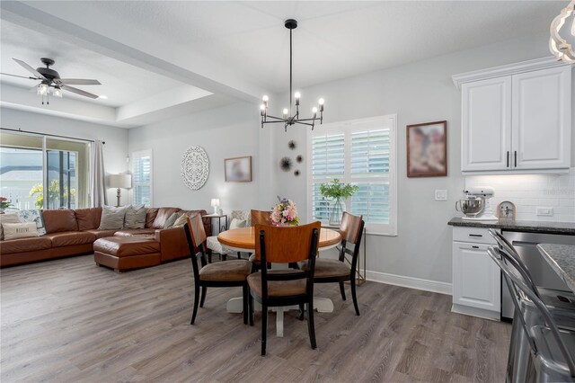 dining room featuring a healthy amount of sunlight, a tray ceiling, baseboards, and wood finished floors