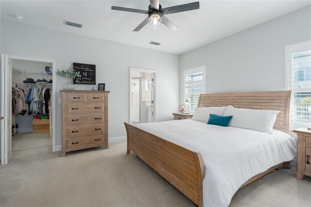 bedroom with visible vents, a ceiling fan, a closet, light colored carpet, and a spacious closet