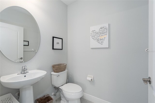 half bath featuring toilet and baseboards