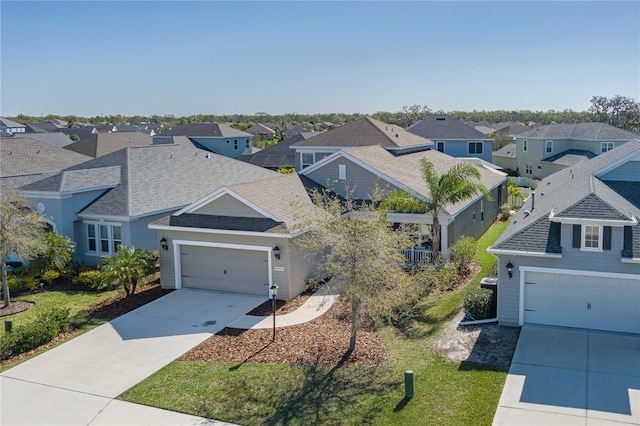 view of front facade with fence, roof with shingles, an attached garage, concrete driveway, and a residential view