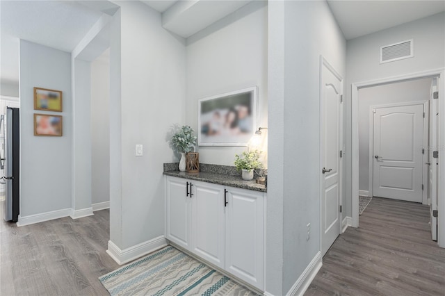 hall featuring baseboards, visible vents, and light wood finished floors