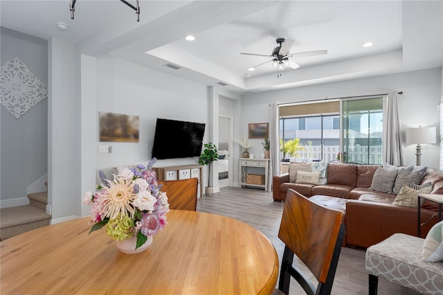 living area with visible vents, recessed lighting, a raised ceiling, and wood finished floors