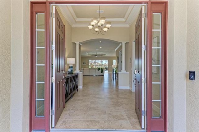 foyer featuring ornate columns, baseboards, ornamental molding, and arched walkways