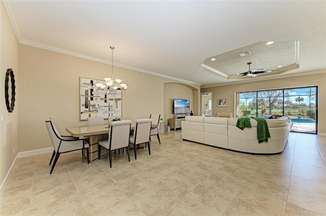 dining space with a tray ceiling, crown molding, visible vents, baseboards, and ceiling fan with notable chandelier