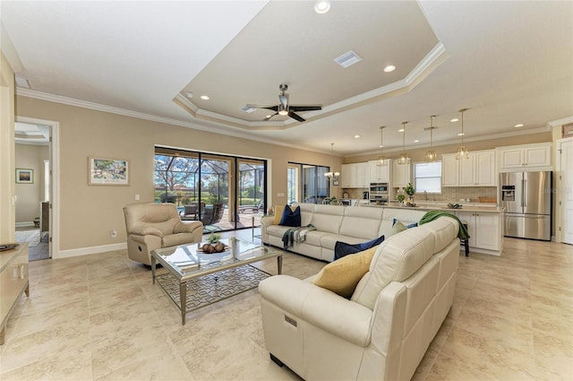 living room with a wealth of natural light, a raised ceiling, ceiling fan, and baseboards