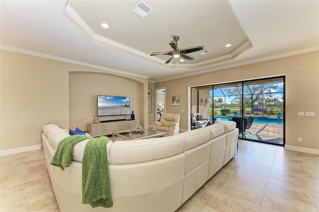 living area featuring crown molding, baseboards, a raised ceiling, and a ceiling fan