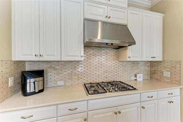 kitchen featuring light countertops, stainless steel gas stovetop, backsplash, white cabinets, and under cabinet range hood