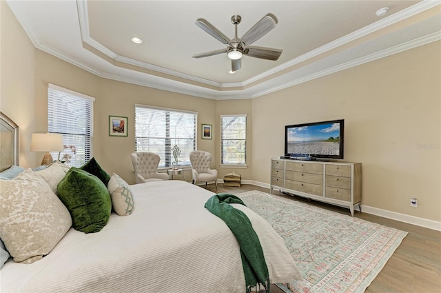 bedroom with baseboards, crown molding, a tray ceiling, and wood finished floors