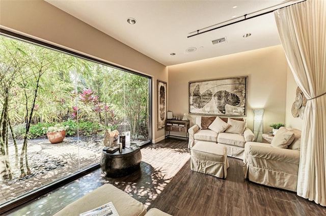 living area with wood finished floors, visible vents, and baseboards