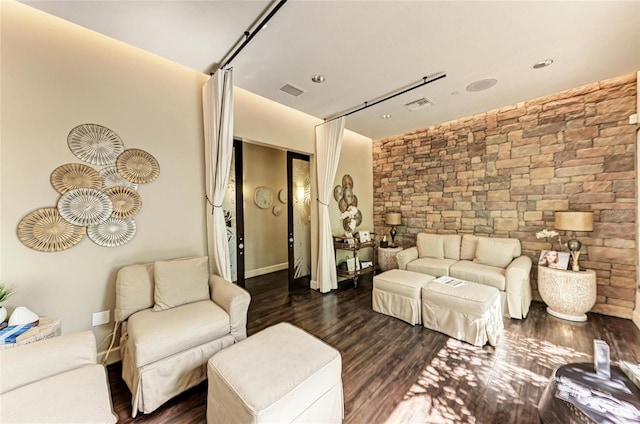 living room with dark wood-type flooring, an accent wall, and visible vents