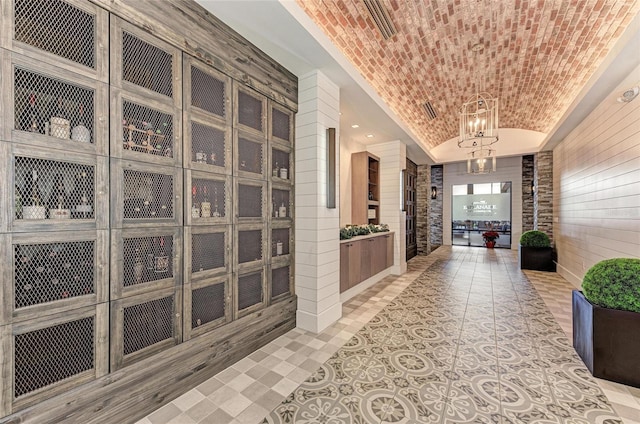 interior space with a chandelier, brick ceiling, lofted ceiling, and wooden walls