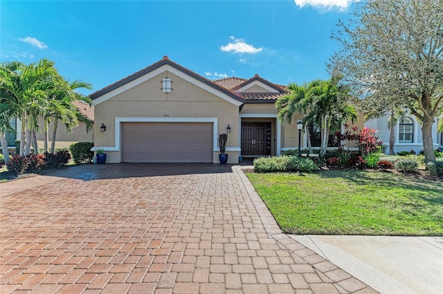 view of front of property featuring decorative driveway, stucco siding, a garage, a tiled roof, and a front lawn