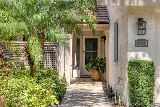 entrance to property featuring a tiled roof and stucco siding