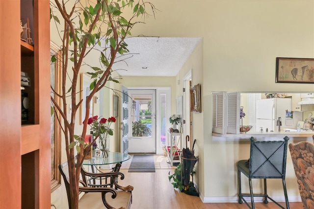 foyer with a textured ceiling, wood finished floors, and baseboards