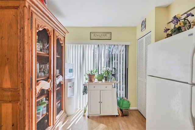 kitchen featuring light wood finished floors, white cabinetry, light countertops, and freestanding refrigerator