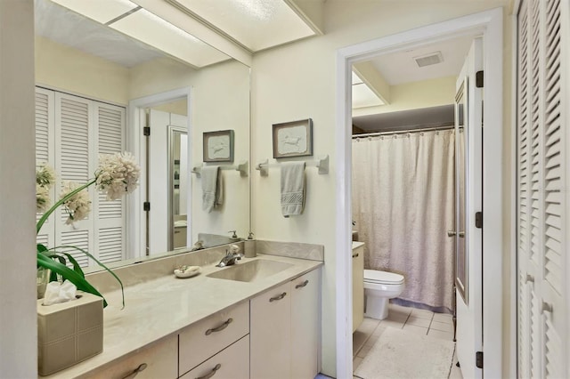 bathroom with a closet, vanity, toilet, and tile patterned floors