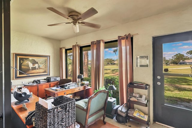 office area with a ceiling fan and a textured wall