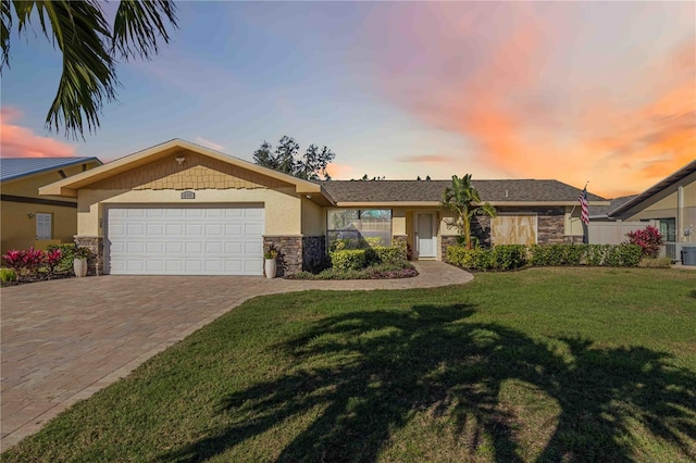 view of front facade with a garage, stone siding, stucco siding, and a front yard