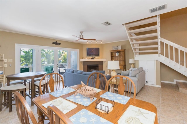 dining space featuring light tile patterned floors, visible vents, a fireplace, and stairs