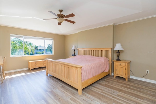 bedroom with light wood-type flooring, crown molding, and baseboards