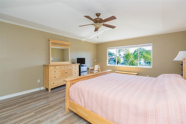 bedroom featuring light wood-type flooring, a ceiling fan, baseboards, and crown molding