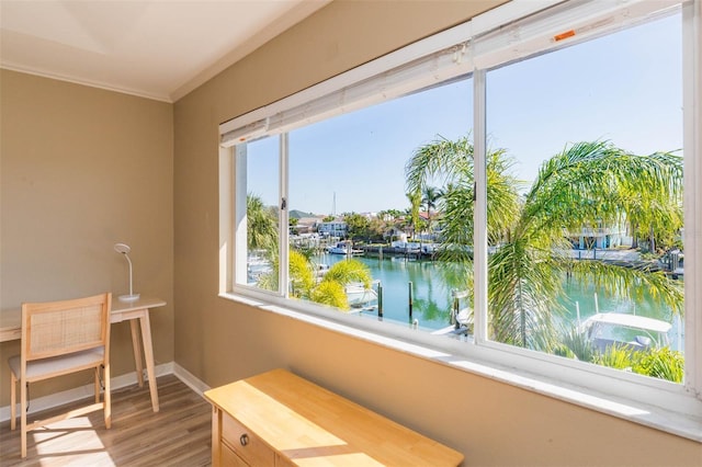 home office featuring baseboards, a water view, wood finished floors, and crown molding