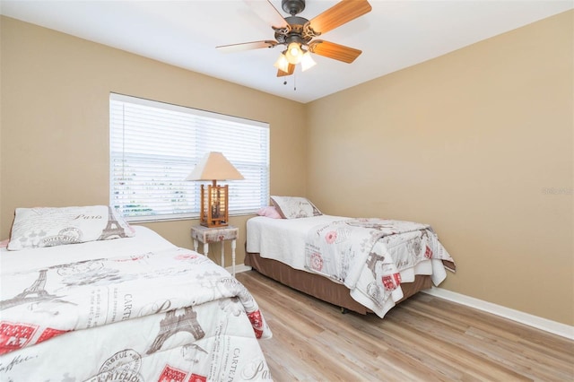 bedroom with a ceiling fan, baseboards, and light wood finished floors